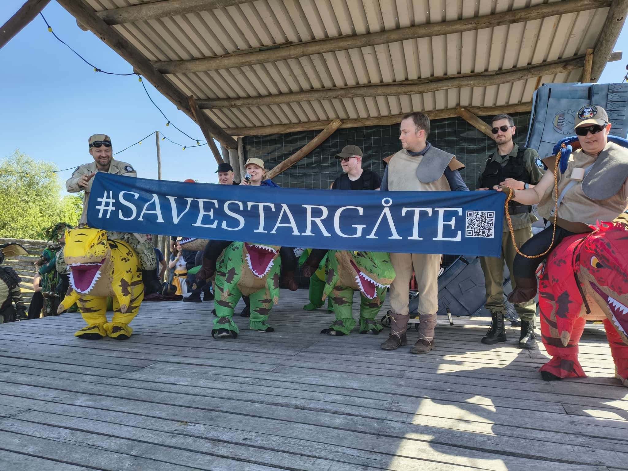 #SaveStargate campaign event with fans holding a banner and dinosaur costumes